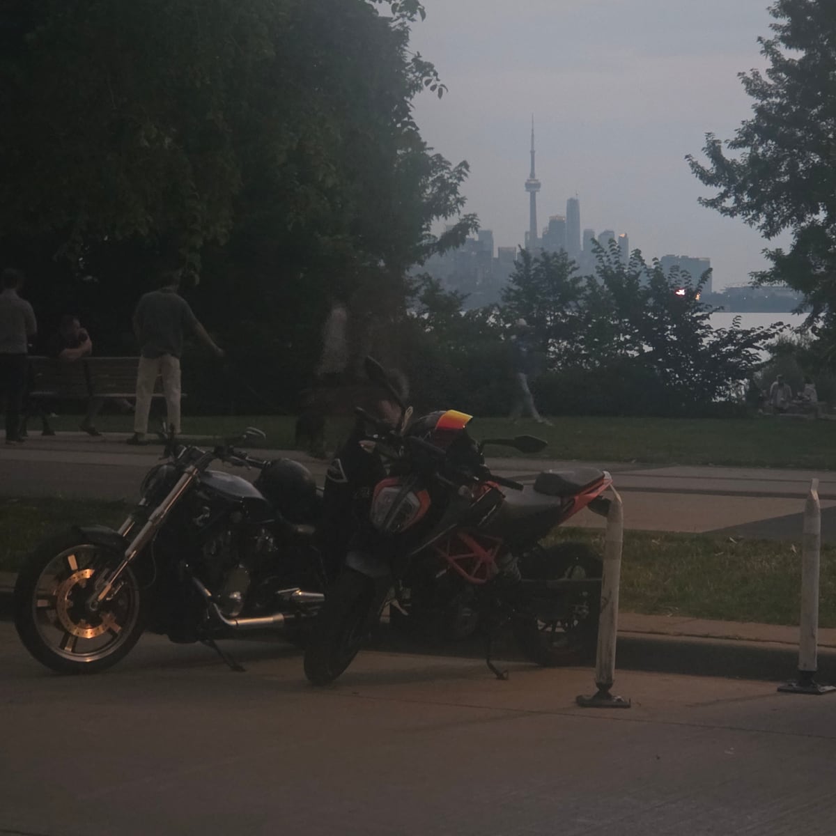 Motorcycles parked at the Toronto waterfront at dusk, CN Tower and downtown skyline in the distance